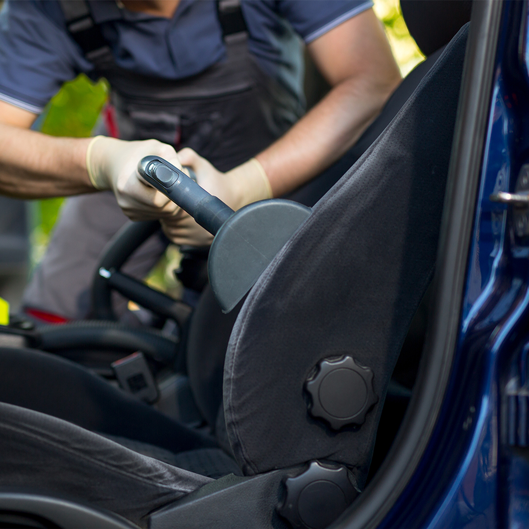 Person vacuuming interior of car