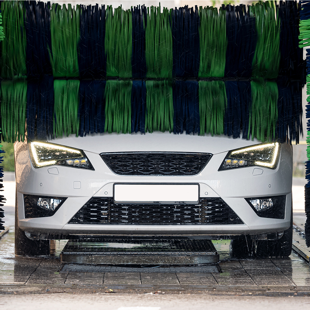 White car going under rollers at car wash